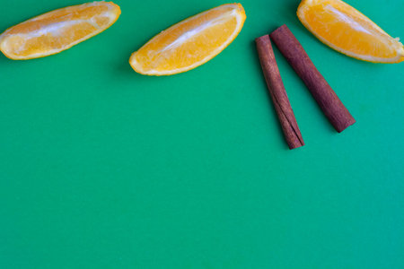 Orange slices and cinnamon sticks on a green background flat lay copy spaceの写真素材