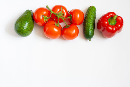 Vegetables on a white background avocado tomatoes on a branch cucumber and sweet pepper copy space