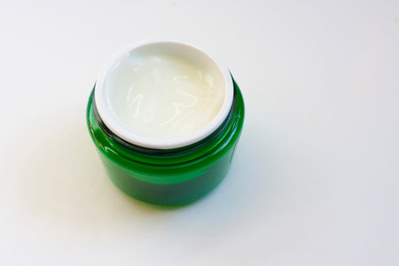 Green jar of cream without a lid isolated on a white background