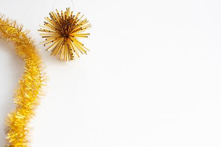 Golden tinsel and Christmas tree toy on a white background copy space