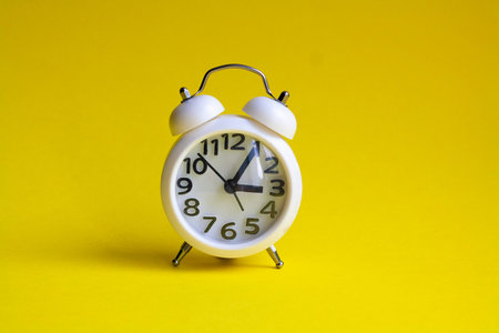 White alarm clock isolated on yellow background
