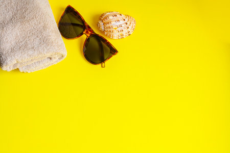 Sunglasses towel and shell on a yellow background copy spaceの写真素材