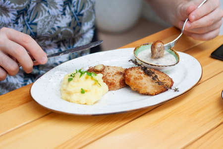 A man eats meat cutlets with mashed potatoes in a restaurantの写真素材