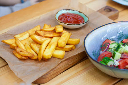French fries with ketchup and vegetable salad in the restaurantの写真素材