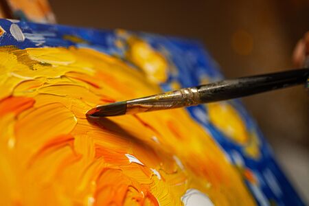 painting with a brush on canvas with blue and orange paint. close-upの写真素材