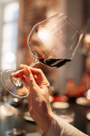 female hand holds a glass with red wine at a tasting in a wine bar