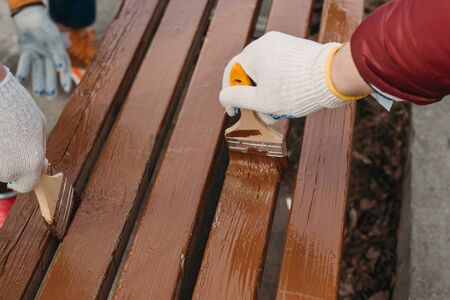 Painting work on the street. A man paints a shop with a paint brush. close-up of handsの写真素材
