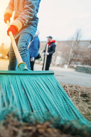 Cleaning of the territory. A man cleans foliage with a broom. Close-up, focus on the broomの写真素材