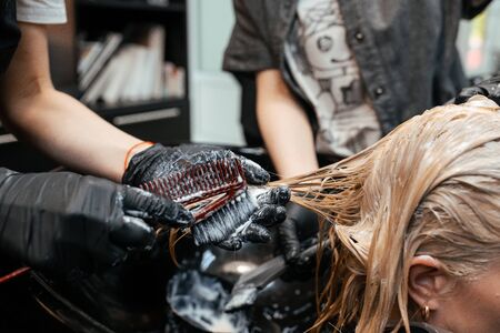 Hairdresser dyes hair in a professional salon. close-up of handsの写真素材