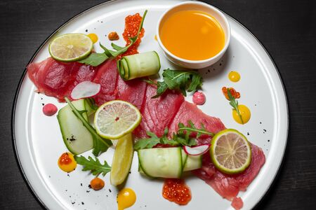 Fresh sliced tuna sashimi with vegetables on a white plate. Top view の写真素材