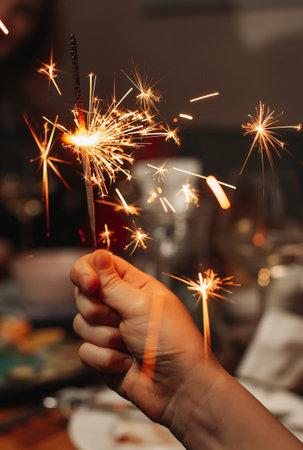 A child holds a burning  sparkler. Close-up without a face