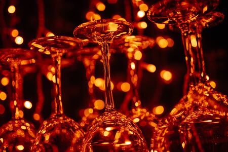 Empty clean drink glasses hang on a bar counter. warm tinting, natural light of barの写真素材