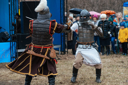 battle reconstruction. Men in armor fight with swords against the background of the audience