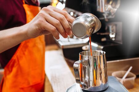 cropped shot of barista preparing coffee in coffee maker. barista man pouring espresso into cupの写真素材