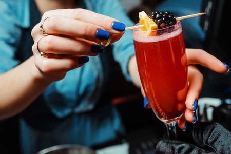 The barman decorates the alcoholic cocktail with berry. Close-upの写真素材