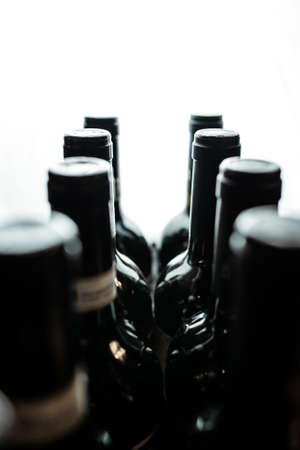 Dark wine bottles stand in a row in backlightの写真素材