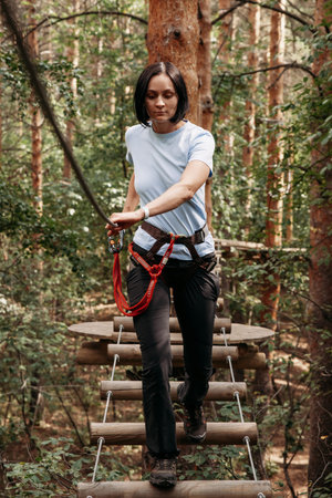 Rope park. A girl with climbing insurance passes the route with obstacles in the rope park.