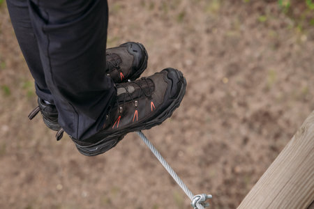 Rope park. A woman in trekking shoes runs a route in a rope park. Close-up of legs