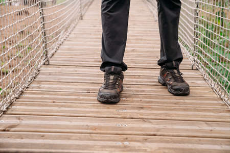 Rope park. A woman in trekking shoes runs a route in a rope park. Close-up of legsの写真素材
