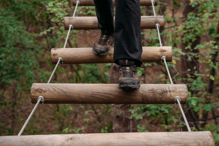Rope park. A woman in trekking shoes runs a route in a rope park. Close-up of legsの写真素材