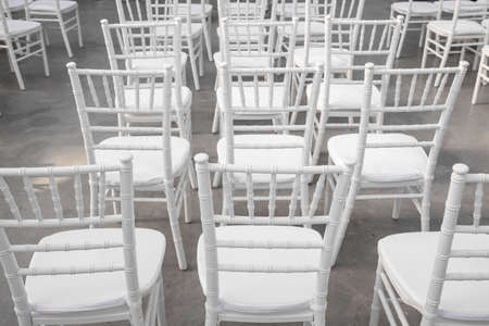 Empty white chairs for guests at a banquet or wedding on an outdoor summer area are in a rowの写真素材