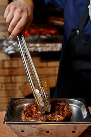 Chef placing cooked meat in a silver dishの写真素材