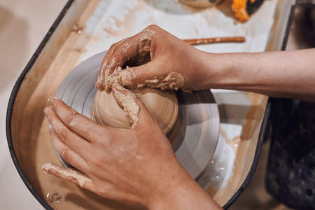 Women working on potters wheel making clay objects in pottery workshopの写真素材