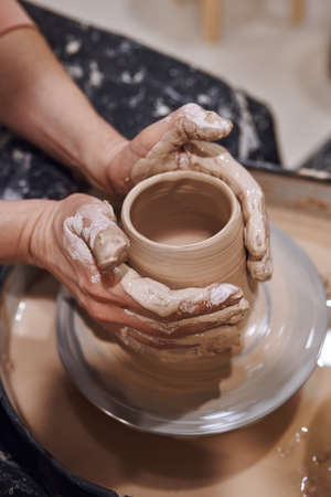 Women working on potters wheel making clay objects in pottery workshopの写真素材