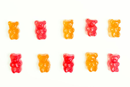 red and orange jelly bears on a white background. pattern, minimalistic background. Treats concept...