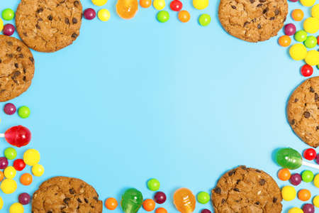 frame of cookies, multicolored candies and lollipops on a blue background. sweets store concept. Beautiful background for the designer. sweets concept for kids. flat lay, copy space.の写真素材