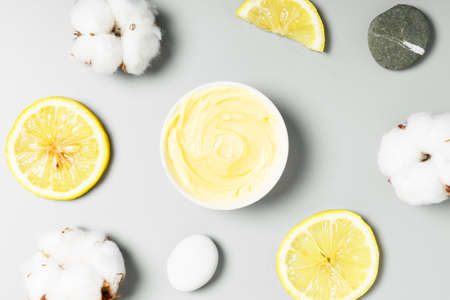  Yellow cream, lemons and cotton on a gray background. natural cosmetics and beauty concept. Top view, flat lay.の写真素材