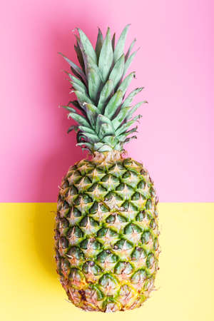 Ripe fresh pineapple on a pink and yellow background. summer concept. top view, minimalismの写真素材