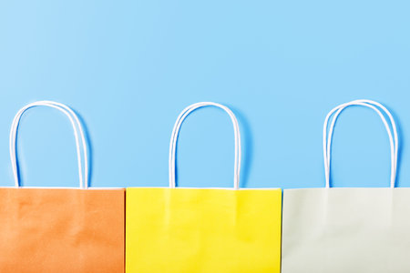 Multicolored paper bag on a light blue background. Shopping and sale concept. Shop shopping concept. Gift wrapping concept. Minimalistic background for the store. Copy space, top view.の写真素材