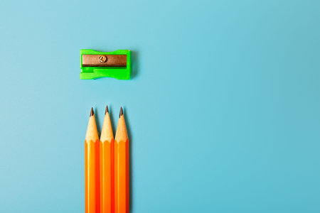 Graphite pencils and a green sharpener on a blue background. Minimalism, copy space, top view.