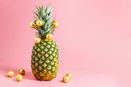 golden christmas balls on pineapple, pink background. pineapple like a christmas tree. Travel concept for christmas or new year. copy space, minimalismの写真素材