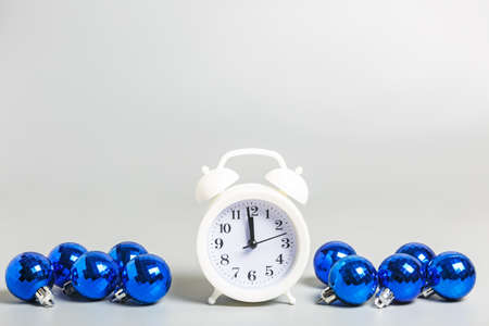 white alarm clock and blue christmas balls on gray background. Christmas or New Year celebration concept. copy space, minimalismの写真素材