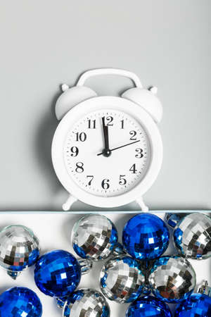 white alarm clock, blue and silver Christmas balls on a gray background. Christmas or New Year concept. top view, flat lay.の写真素材