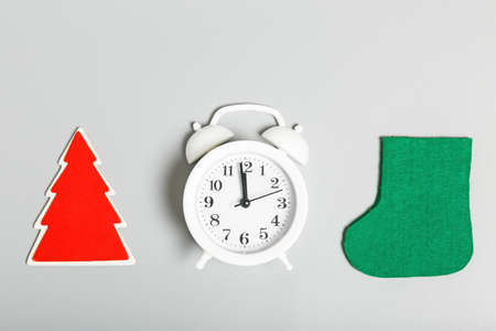 White alarm clock, red wooden Christmas tree and green felt boots on a gray background. Christmas or new year concept. top view, flat lay, minimalismの写真素材