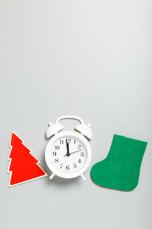 White alarm clock, red wooden Christmas tree and green felt boots on a gray background. Christmas or new year concept. top view, flat lay, copy space, vertical, minimalismの写真素材