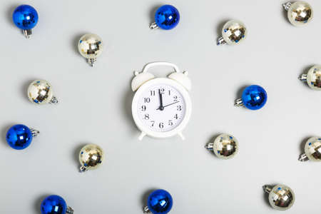 Pattern of white alarm clock, blue and silver Christmas balls on a gray background. Christmas or New Year celebration concept. top view, flat layの写真素材