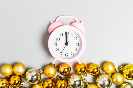 pink alarm clock and golden christmas balls on gray background. Christmas or New Year concept. top...