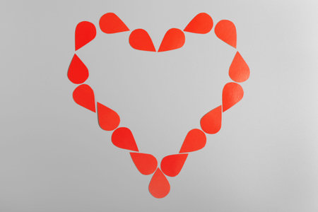 Red heart made of drops on a gray background. Blood Donor Day. Love and caring. Copy space.