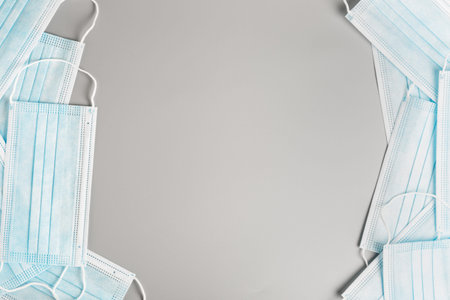 frame from blue medical surgical masks on a gray background. concept of protection against coronavirus during a pandemic and quarantine. copy space, flat layの写真素材