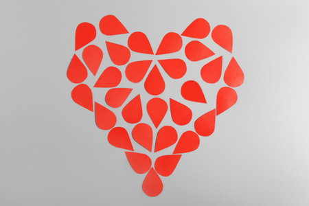 Red heart made of drops on a gray background. Blood Donor Day. Love and caring.