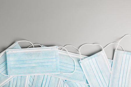 A lot of blue medical surgical masks on an gray background. concept of protection against virus...