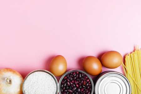 Eggs, rice, beans, pasta, canned food on a pink background. Concept of food delivery and food donation during quarantine isolation during the coronavirus pandemic. online grocery shopping. copy spaceの写真素材
