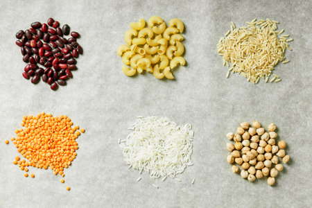 Red lentils, white rice, beans, pasta and chickpeas on a grey background. Healthy food concept. Ingredients for cooking.の写真素材