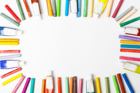 frame of colorful pastel crayons and tubes of oil paint on a white background. concept of drawing...