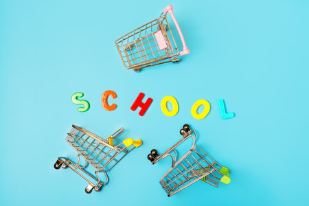 Empty shopping carts trolleys and the word school of multicolored letters on a blue background. Concept for a store of goods for school and education. Sale and discount concept.の写真素材