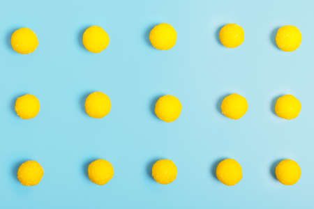 Yellow round candies on a blue background. sweets store concept. Beautiful background pattern for the designer. top view, minimalism.の写真素材
